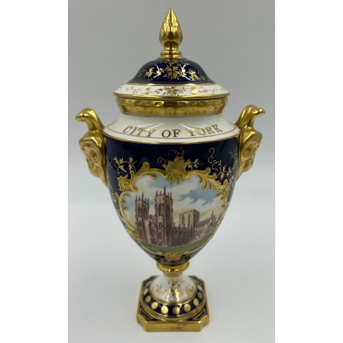 197 - Coalport: Two twin-handled commemorative urn shaped vases with covers and twin goat head handles, on... 