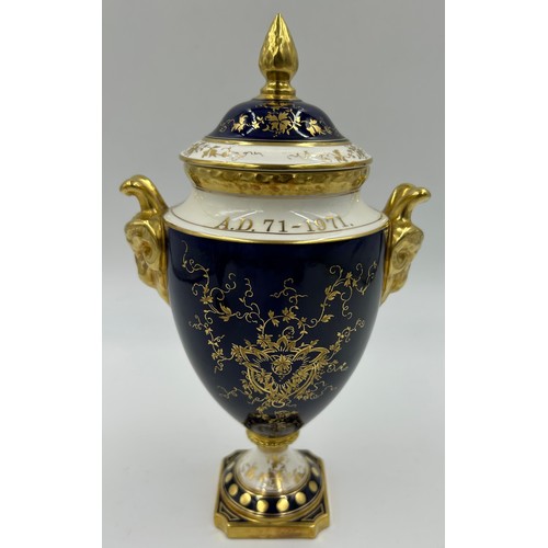 197 - Coalport: Two twin-handled commemorative urn shaped vases with covers and twin goat head handles, on... 