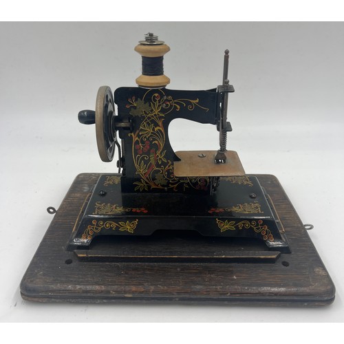 1302 - A child’s metal sewing machine in an oak Edison case. 25cm w x 22cm h.