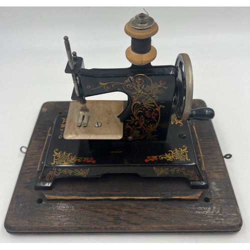 1302 - A child’s metal sewing machine in an oak Edison case. 25cm w x 22cm h.