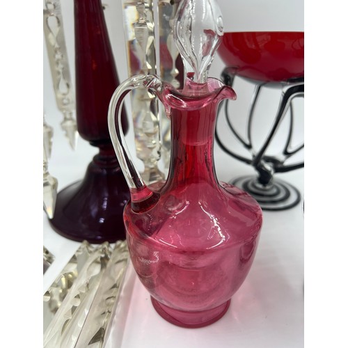 299 - Glass to include a ruby glass lustre with extra drops, cranberry glass jug and two art glass vases.