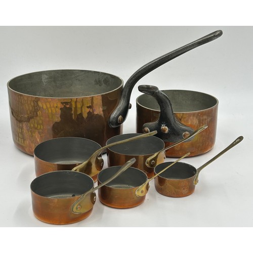 415 - Set of 7 French copper pans, the larger two with cast iron handles, the smaller ones with brass hand... 