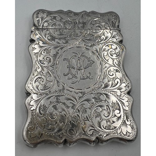 912 - A silver card case with foliage scroll engraving and initials to front. 9cm x 6.5cm. Birmingham 1902... 