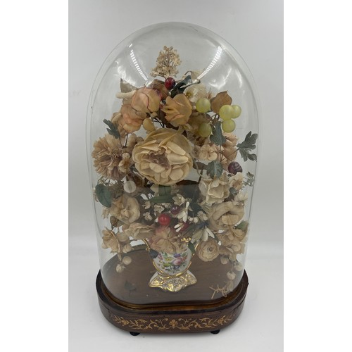 1313 - A glass display dome containing a vintage floral display in continental ceramic vase on an inlaid ro... 