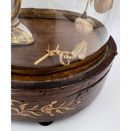 1313 - A glass display dome containing a vintage floral display in continental ceramic vase on an inlaid ro... 