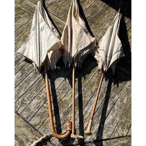 704 - Three Victorian bamboo parasols to include one with embroidered fabric and a carved swan handle and ... 