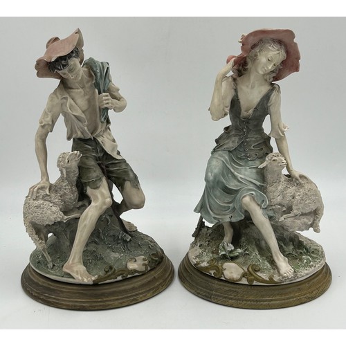 121 - Two Giuseppe Armani  Capodimonte figures of a lady and a gent, seated with sheep on wooden plinths. ... 