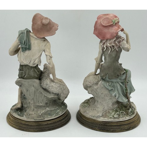 121 - Two Giuseppe Armani  Capodimonte figures of a lady and a gent, seated with sheep on wooden plinths. ... 