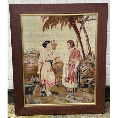 723 - An oak framed needlepoint tapestry depicting a shepherd and a water carrier. Tapestry 63 x 50cm.