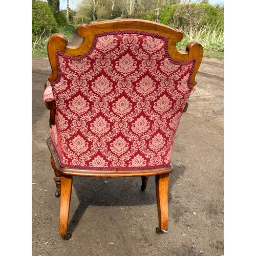 63 - An upholstered armchair with turned reeded legs and brass castors together with abutting footstool t... 