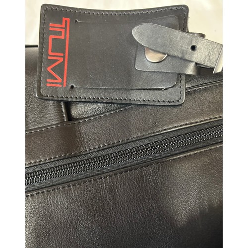 725 - A Tumi black leather briefcase/laptop bag together with a black Tumi suit carrier with leather handl... 