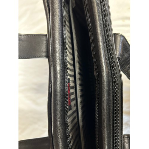 725 - A Tumi black leather briefcase/laptop bag together with a black Tumi suit carrier with leather handl... 