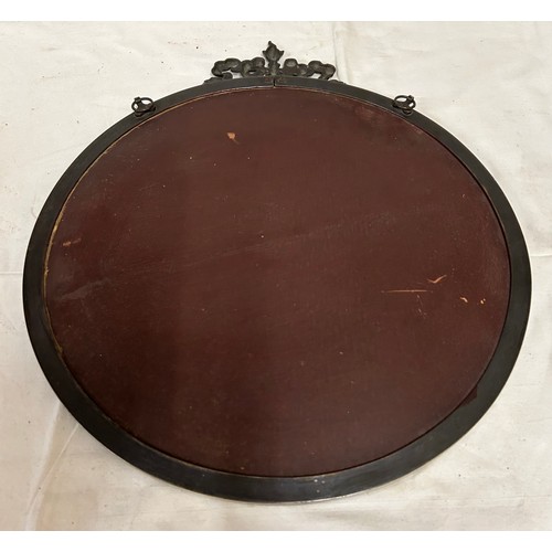 1097 - A heavy circular metal bevelled mirror with bowed ribbon decoration to the top. 48.5cm d, 56cm h wit... 