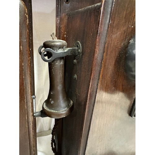 1281 - Two wooden cased wall mounted telephones, with mouth piece to the left hand side, crank handle to th... 