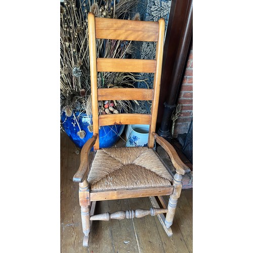 130 - A rush seated ladder back rocking chair.