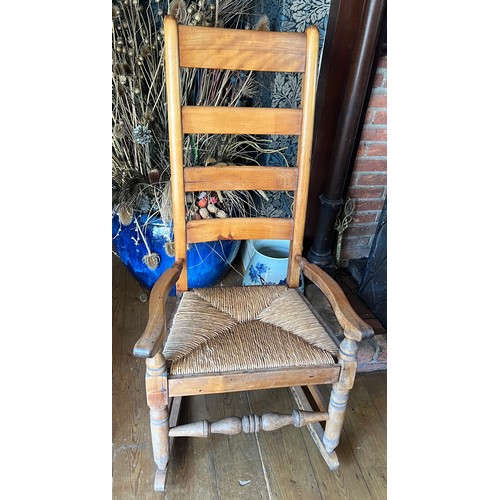 130 - A rush seated ladder back rocking chair.