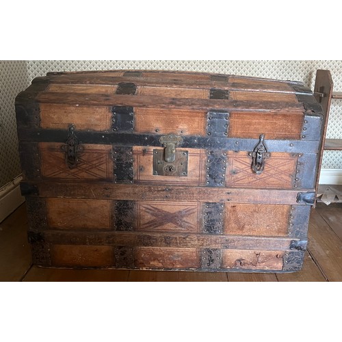 123 - A dome topped leather covered trunk with metal and wooden binding. 76cm x 44cm x 52cm.