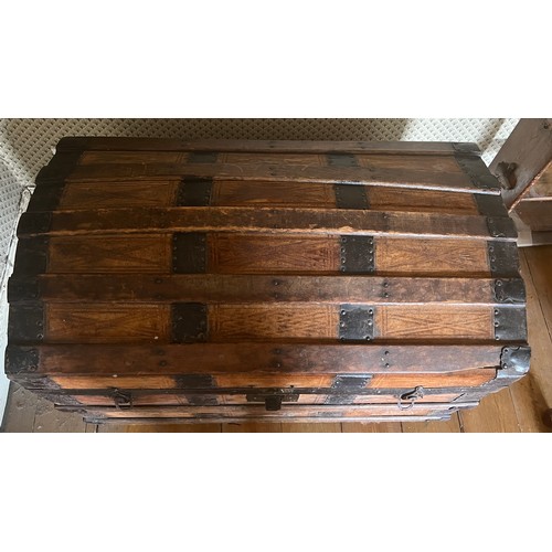 123 - A dome topped leather covered trunk with metal and wooden binding. 76cm x 44cm x 52cm.