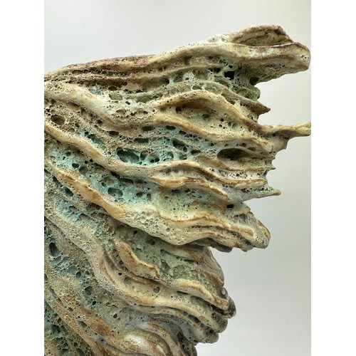 334 - Wendy Lawrence; a carved stoneware sculpture layered with textured volcanic glazes on a stone base, ... 