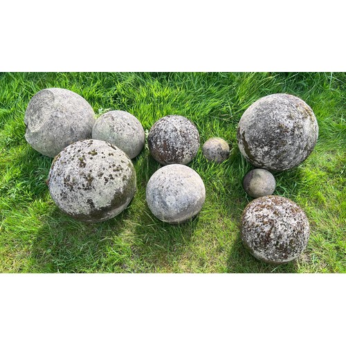 13 - Nine reconstituted stone balls and a plaque. Largest approx. 38cm.