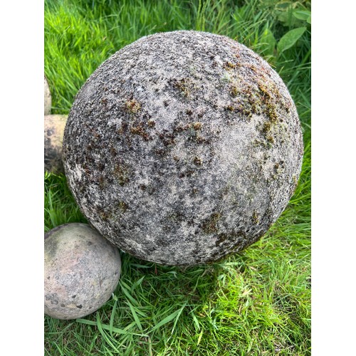 13 - Nine reconstituted stone balls and a plaque. Largest approx. 38cm.