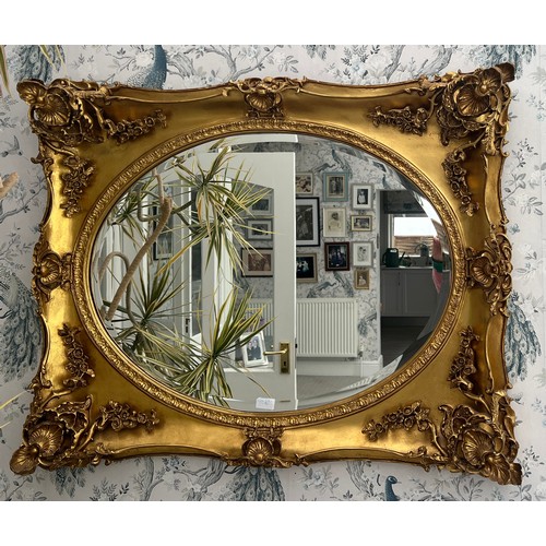 1235 - An oval bevel edged wall mirror in deep decorative gilt frame. 80 x 99cm.