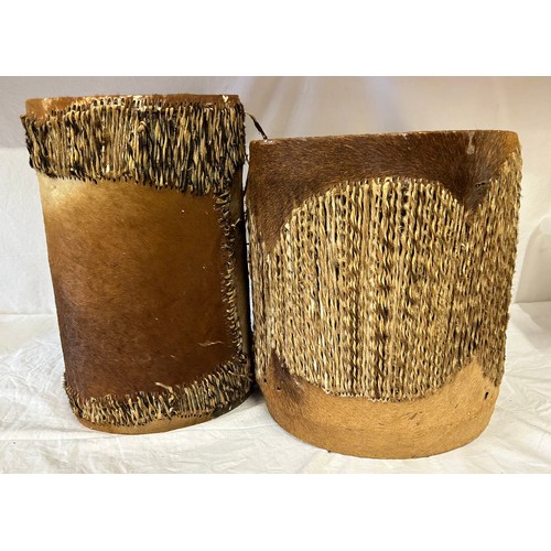 981 - Two traditional African cow hide drums. Tallest 42cm x 26cm, other 36cmx31cm. Rush decoration to edg... 