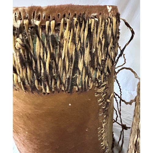 981 - Two traditional African cow hide drums. Tallest 42cm x 26cm, other 36cmx31cm. Rush decoration to edg... 