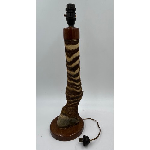 1019 - A taxidermy table lamp formed from a zebra leg on a wooden base together with a carved wooden lion t... 