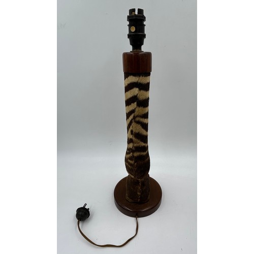 1019 - A taxidermy table lamp formed from a zebra leg on a wooden base together with a carved wooden lion t... 