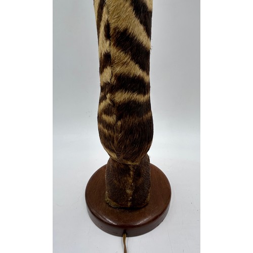 1019 - A taxidermy table lamp formed from a zebra leg on a wooden base together with a carved wooden lion t... 