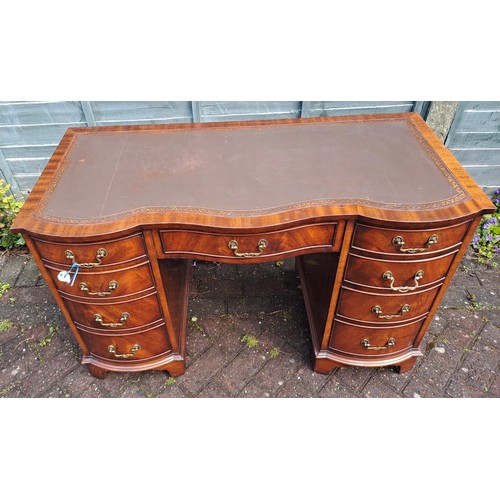 102 - A mahogany kneehole desk with serpentine front and tooled leather top. 115cm w x 53cm d x 75cm h.