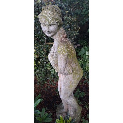 14 - A reconstituted stone garden statue depicting a coy female in a state of semi undress. 118cm h.