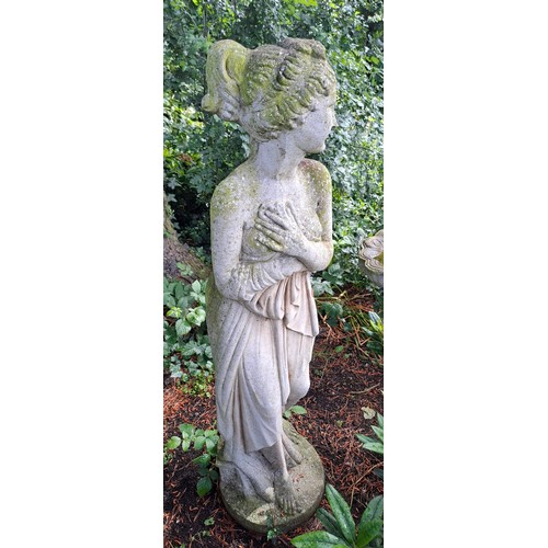 14 - A reconstituted stone garden statue depicting a coy female in a state of semi undress. 118cm h.