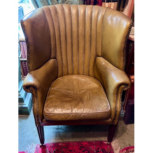 85 - A leather barrel armchair on square tapered legs and brass castors. Height to back 110cm, 77cm w.