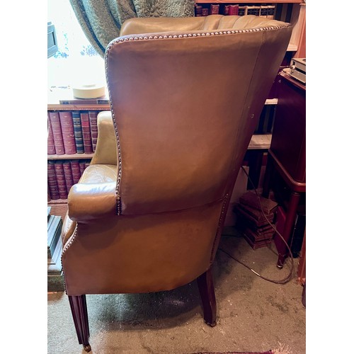 85 - A leather barrel armchair on square tapered legs and brass castors. Height to back 110cm, 77cm w.