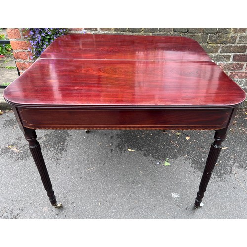 70 - A Gillows mahogany fold over tea table on reeded legs with brass castors. 91cm w x 45cm d x 75cm h. ... 