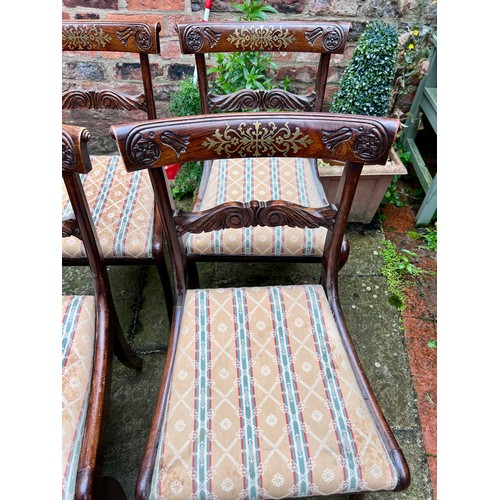 71 - Four Regency rosewood sabre legged dining chairs with brass inlay to back and drop in seats.