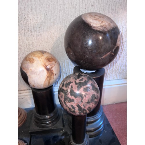 1269 - Eight various marble, granite and wooden balls displayed on plinths. Largest ball 39cm h on plinth.