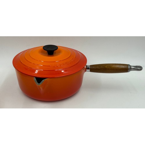 955 - A quantity of Le Creuset volcanic orange to include : three lidded enamelled pans, 22cm, 18cm and 16... 