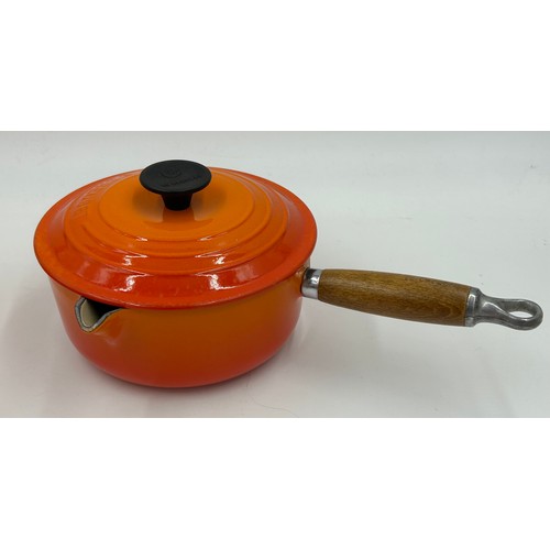 955 - A quantity of Le Creuset volcanic orange to include : three lidded enamelled pans, 22cm, 18cm and 16... 