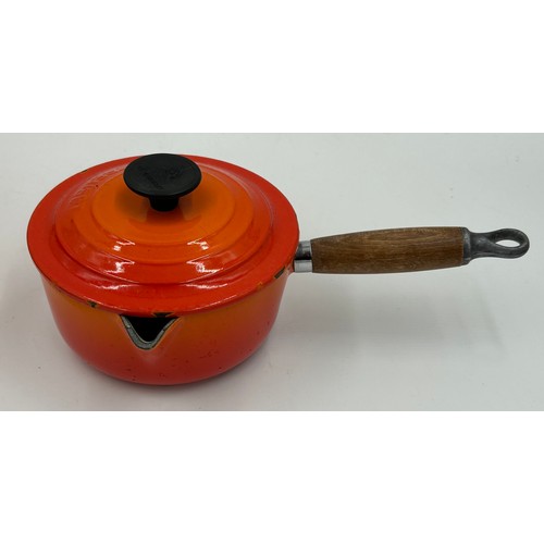 955 - A quantity of Le Creuset volcanic orange to include : three lidded enamelled pans, 22cm, 18cm and 16... 