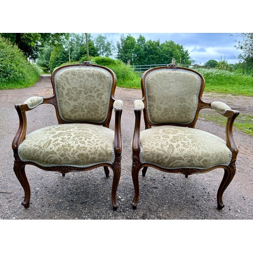 65 - Two upholstered open armchairs/fauteuils in the French style with cabriole legs to front and floral ... 