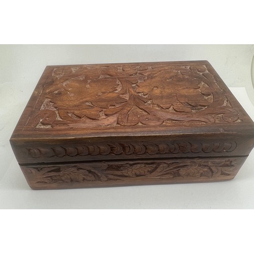 581 - A carved wooden box and costume jewellery contents to include silver rings, brooches, pendants etc.