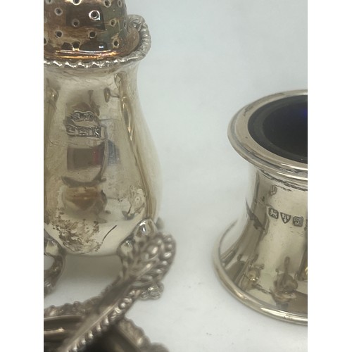 772 - A three piece silver cruet set comprising salt, pepper, mustard and two spoons plus a single salt an... 