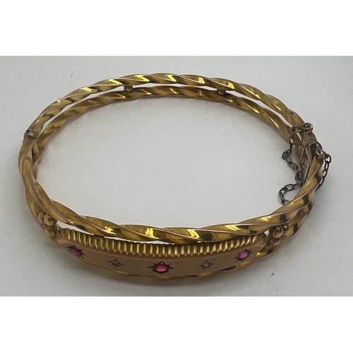 656 - A nine carat gold hinged bangle set with pink and clear stones in original fitted case. Weight 7.4gm... 