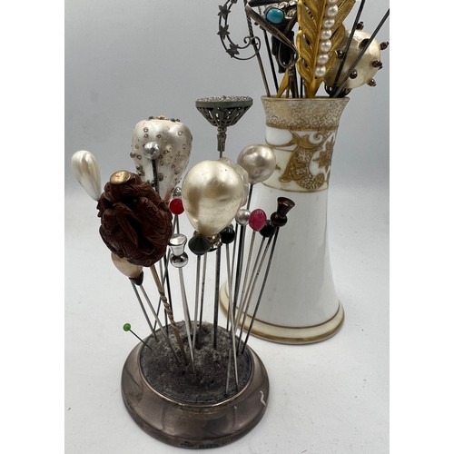 616 - A collection of hatpins and two hatpin holders, one silver and one Noritake to include silver teddy,... 