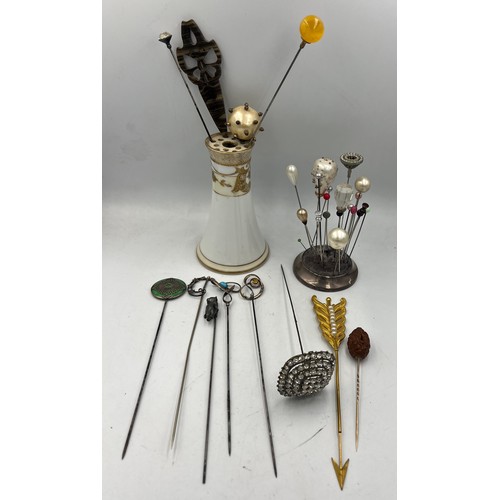 616 - A collection of hatpins and two hatpin holders, one silver and one Noritake to include silver teddy,... 