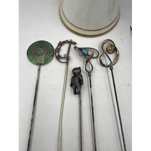 616 - A collection of hatpins and two hatpin holders, one silver and one Noritake to include silver teddy,... 