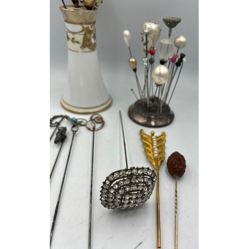 616 - A collection of hatpins and two hatpin holders, one silver and one Noritake to include silver teddy,... 